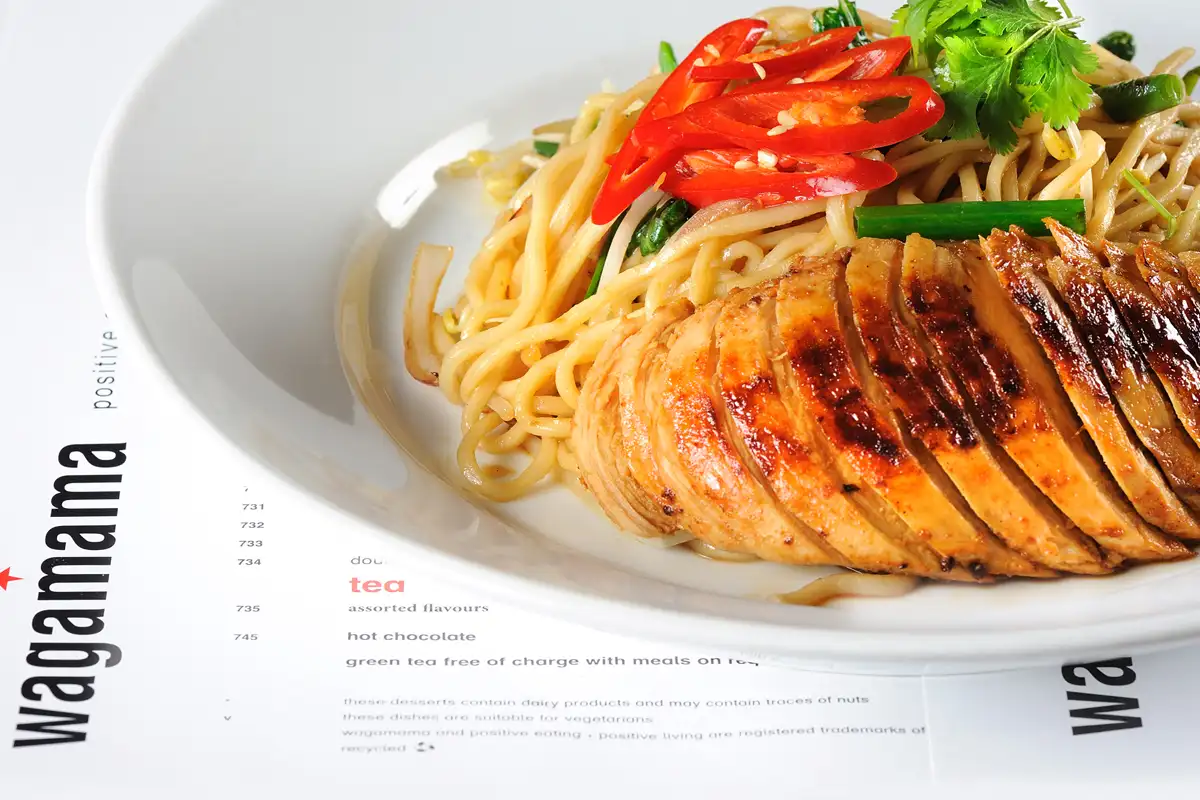 Sliced glazed chicken over stir-fried noodles with chili and coriander — Asian cuisine photography Dubai