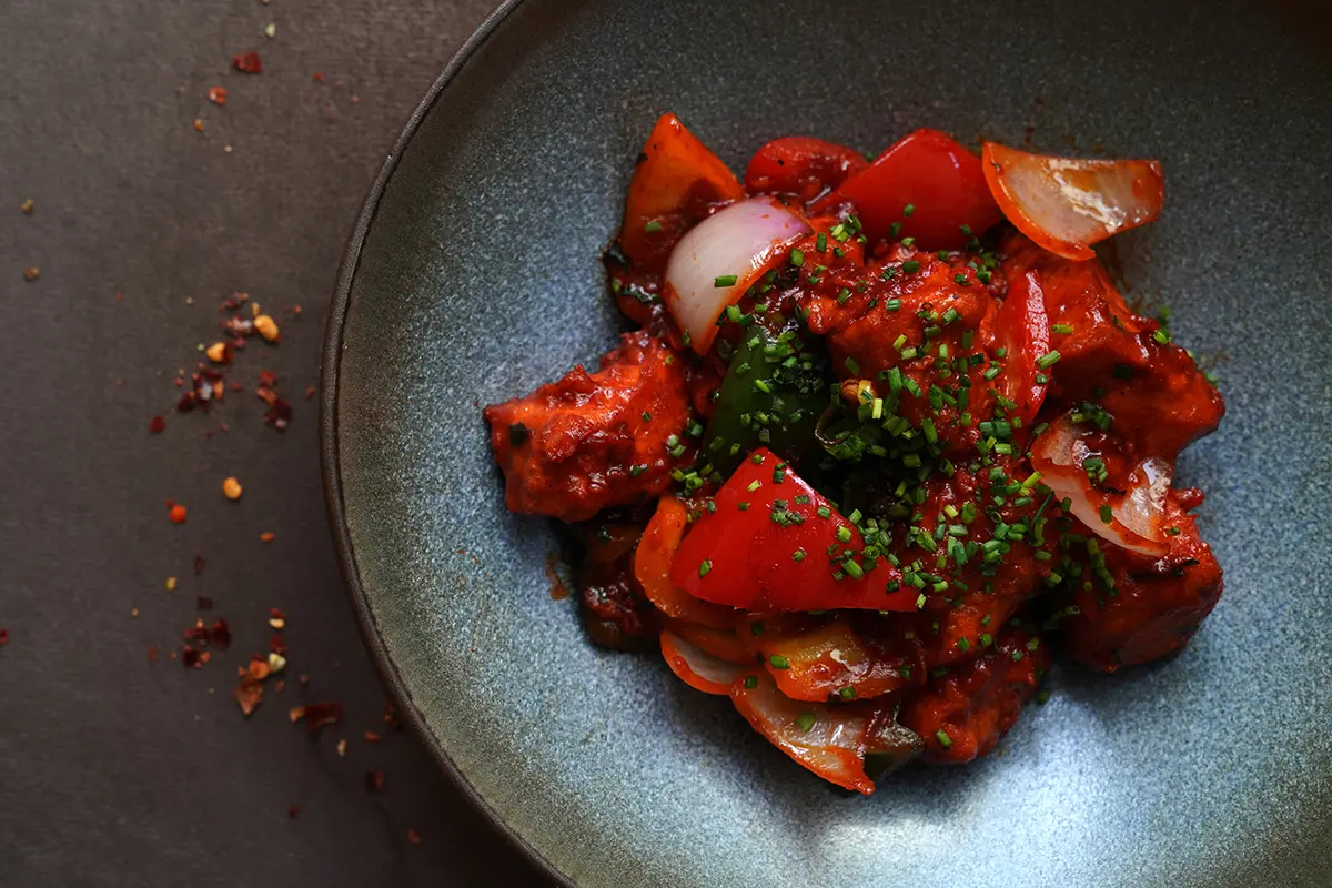 Chili chicken tossed with peppers and onions — restaurant photography Dubai