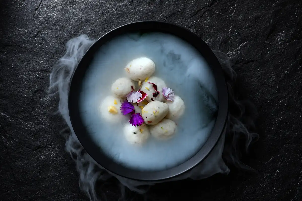 Rasgulla dessert with edible flowers served tableside with dry ice — dessert photography Dubai