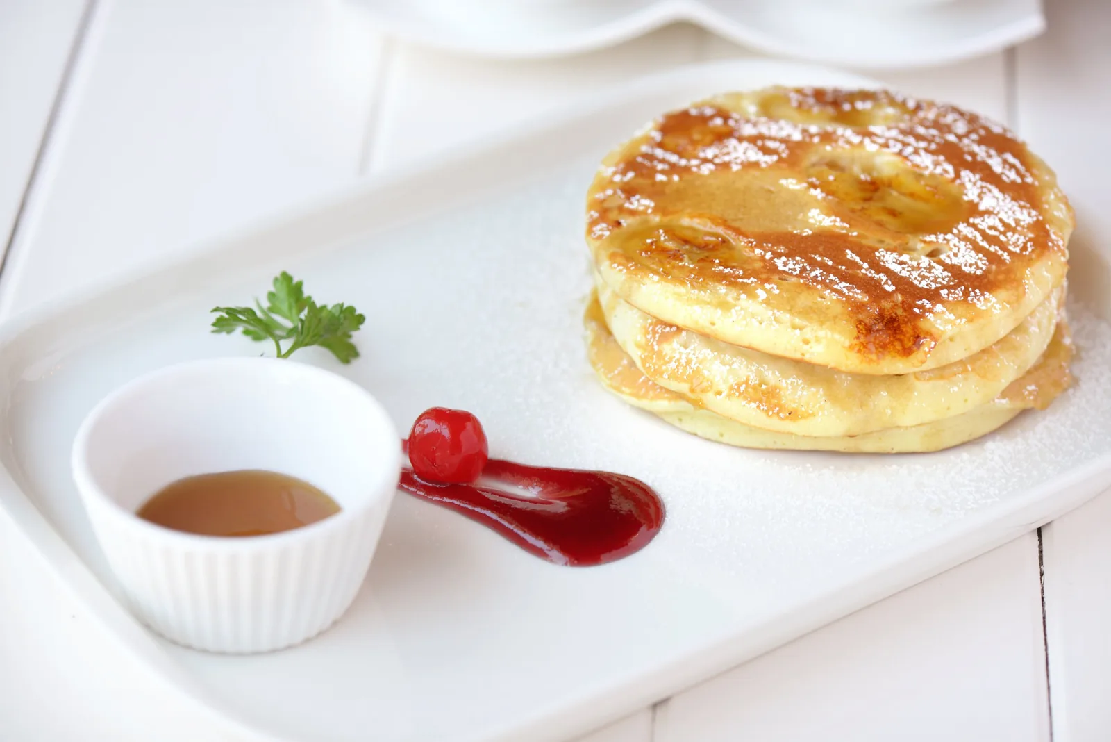 Golden pancake stack with powdered sugar, maple syrup and berry coulis — Dubai dessert photography