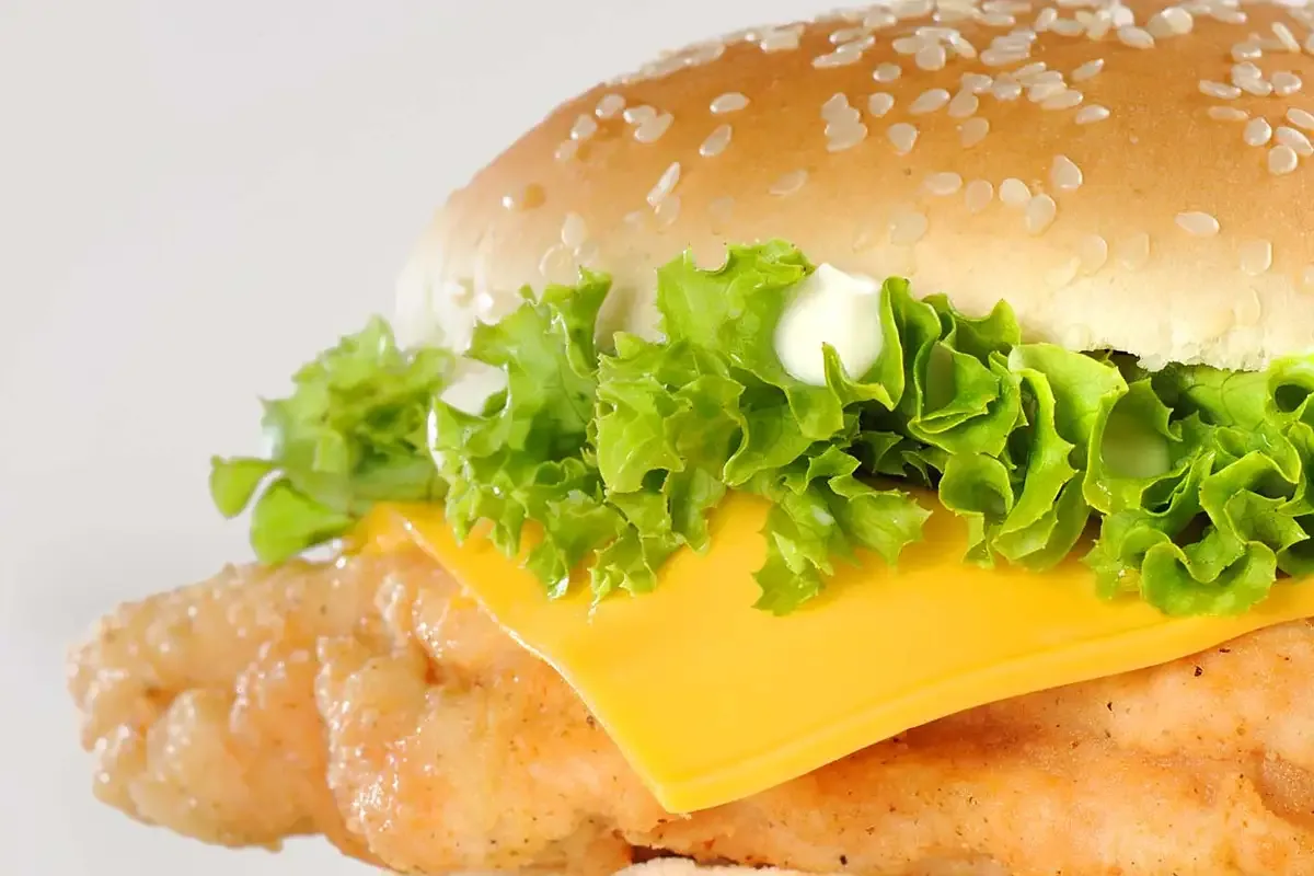 Close-up of a crispy chicken burger with lettuce and cheese, food photography for a Jeddah restaurant menu